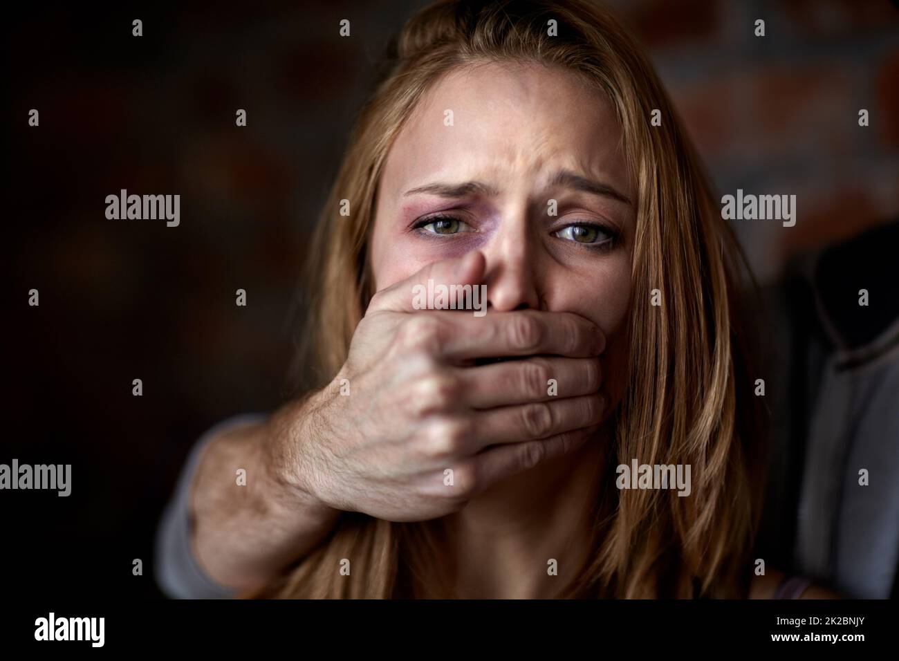 Silent destroyer. Abused young woman being silenced by her abuser. Stock Photo