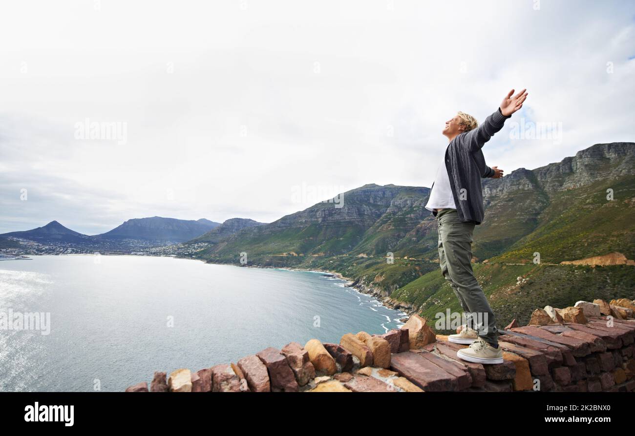 Embracing the magnificence of nature. Shot of a young man standing on a wall looking at the natural scenery. Stock Photo