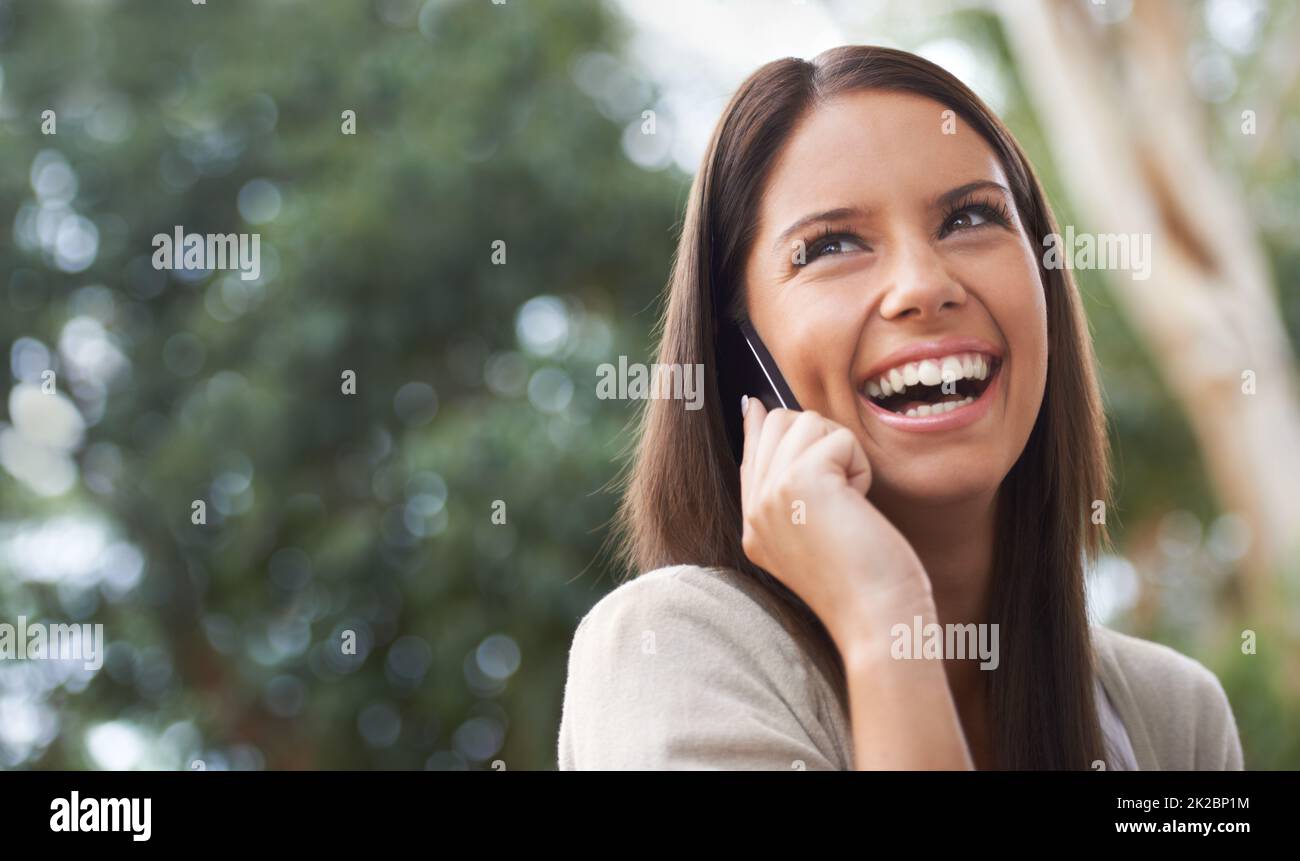 On the phone to her Best Friend. A pretty young woman enjoying a conversation in the park. Stock Photo