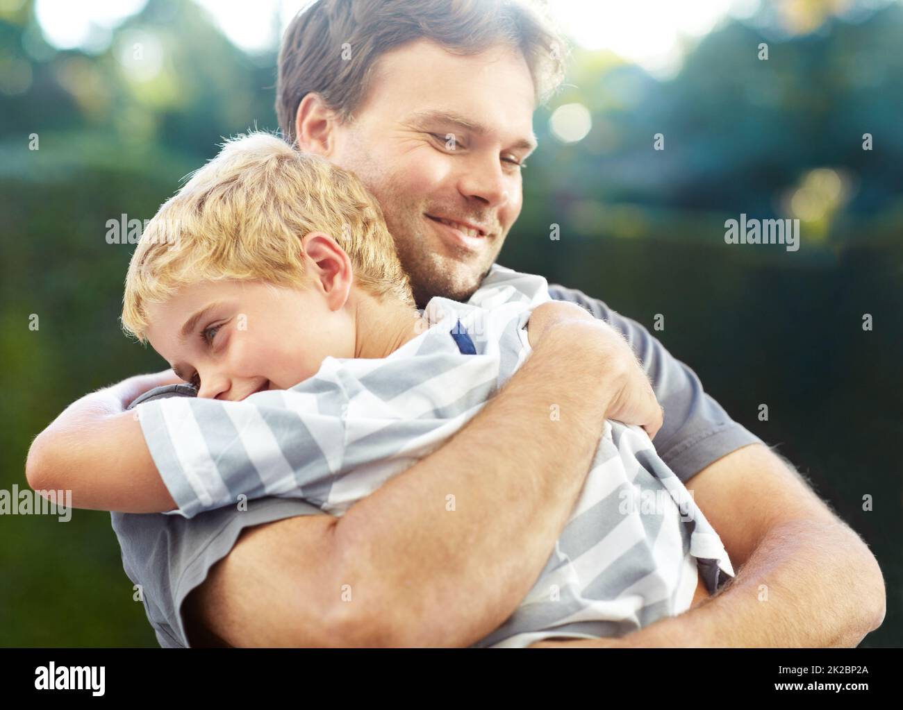 Daddys boy. Shot of a smiling father hugging his son outside. Stock Photo