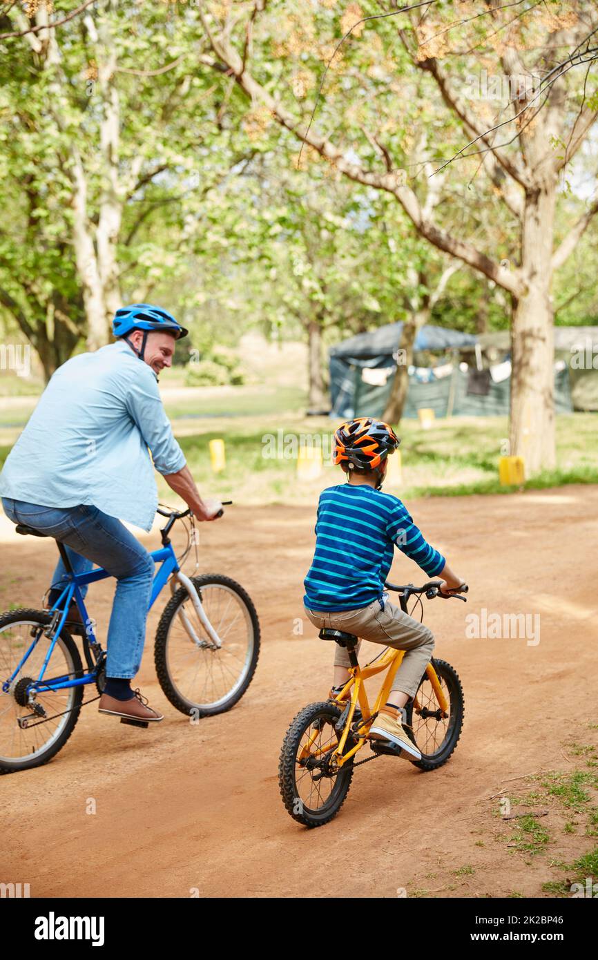 Fresh air and exercise with the boys. Shot of a father and his young son riding bicycles through a park. Stock Photo