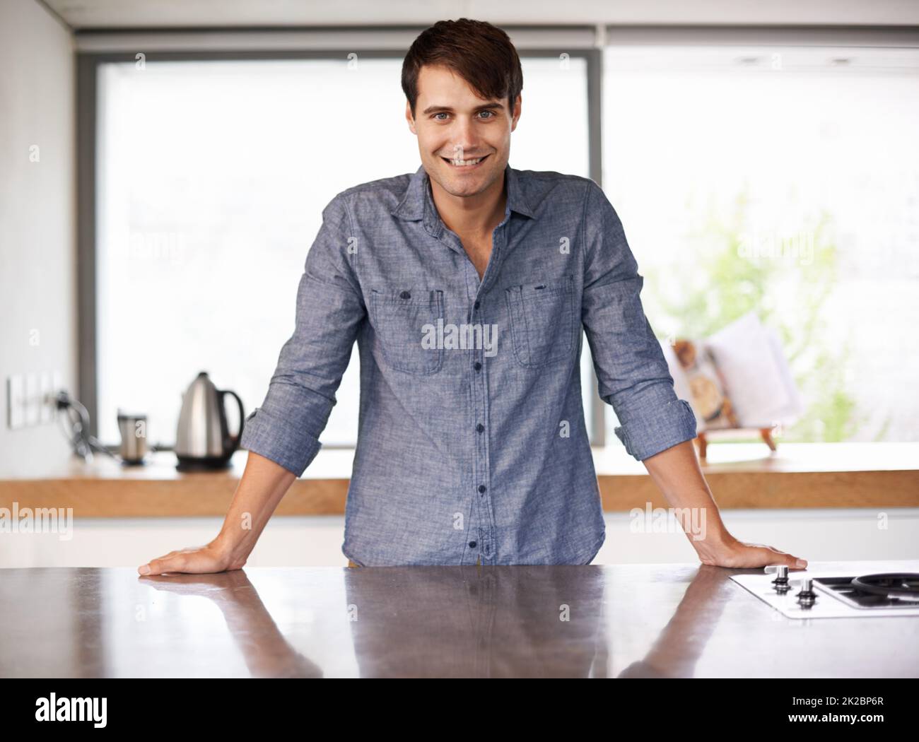 There is no place like home. Portrait of a handsome young man standing behind his kitchen countertop. Stock Photo