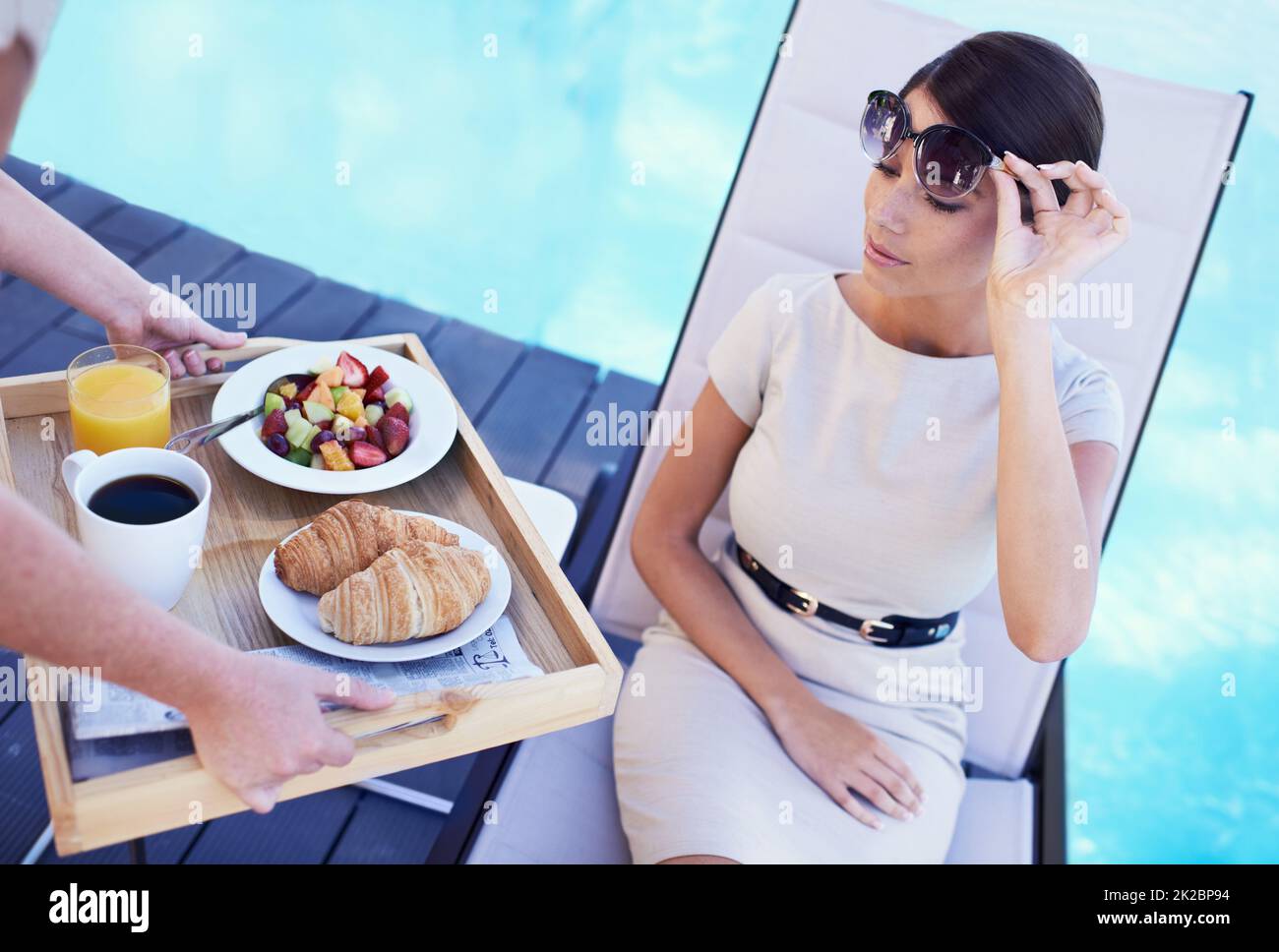 Relaxing while on holiday. A posh young woman looking dubiously at the food brought to her. Stock Photo