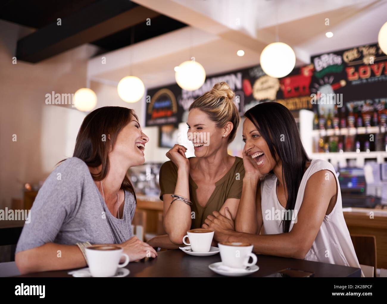 Catching up on the news. Shot of three friends having fun at a coffee shop together. Stock Photo