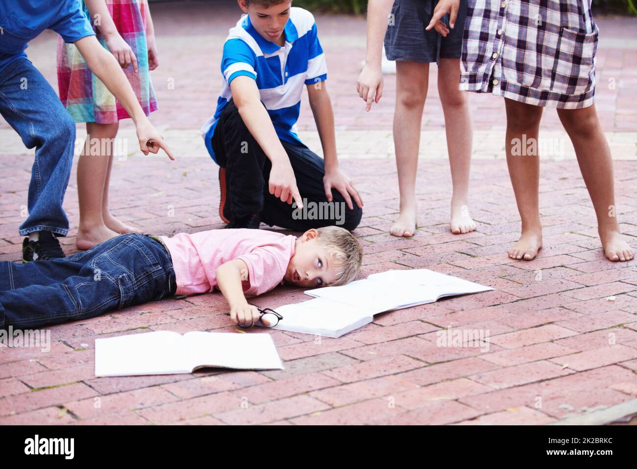 Youre such a nerd - Bullying. Shot of a young boy being picked on by a bunch of schoolkids. Stock Photo