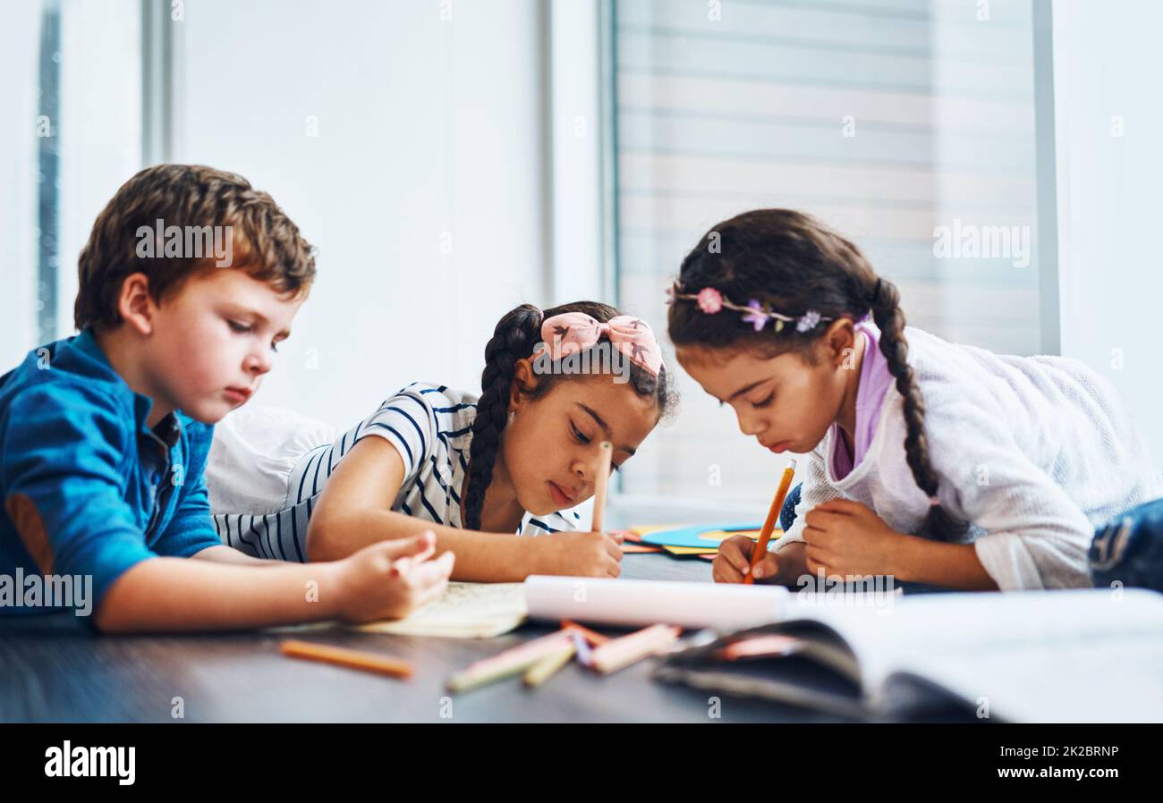 Its so easy to get them to be calm. Cropped shot of kids coloring in while lying on the floor. Stock Photo