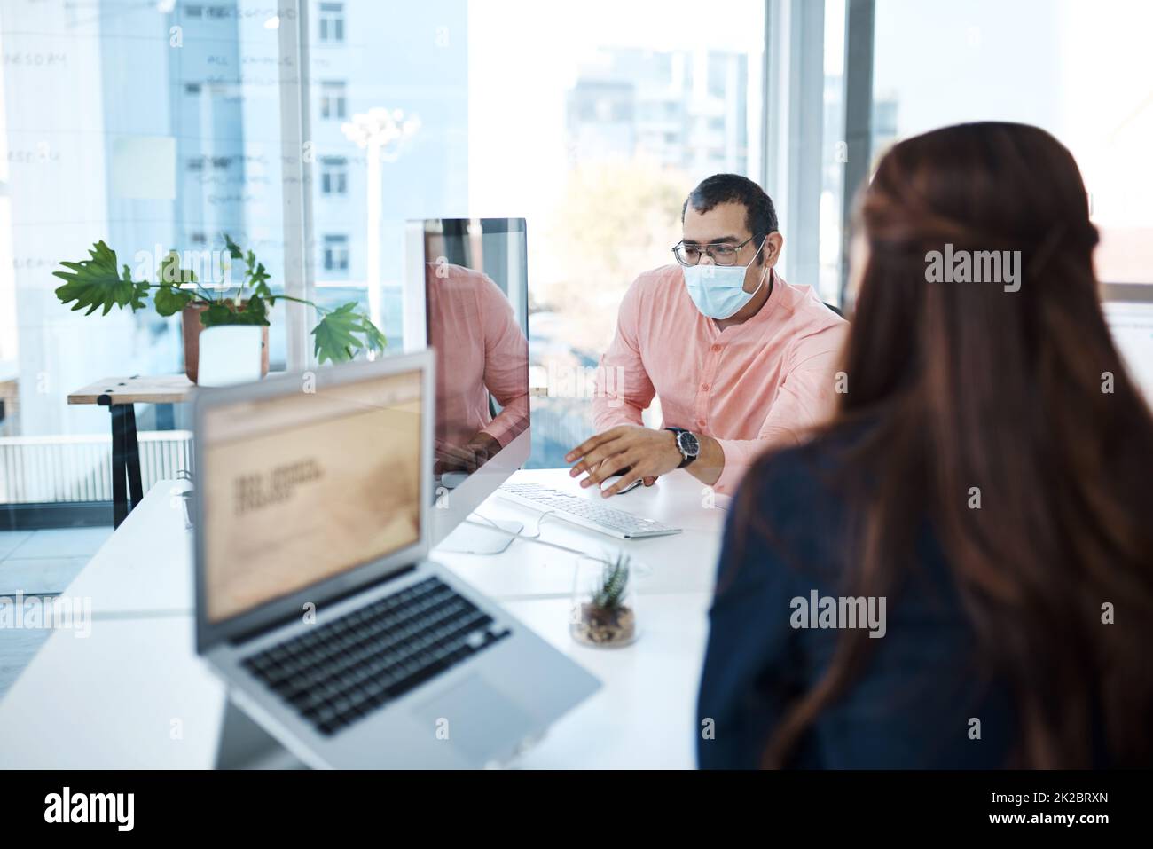 Staying shielded while achieving success. Shot of two businesspeople wearing face masks while working together in an office. Stock Photo