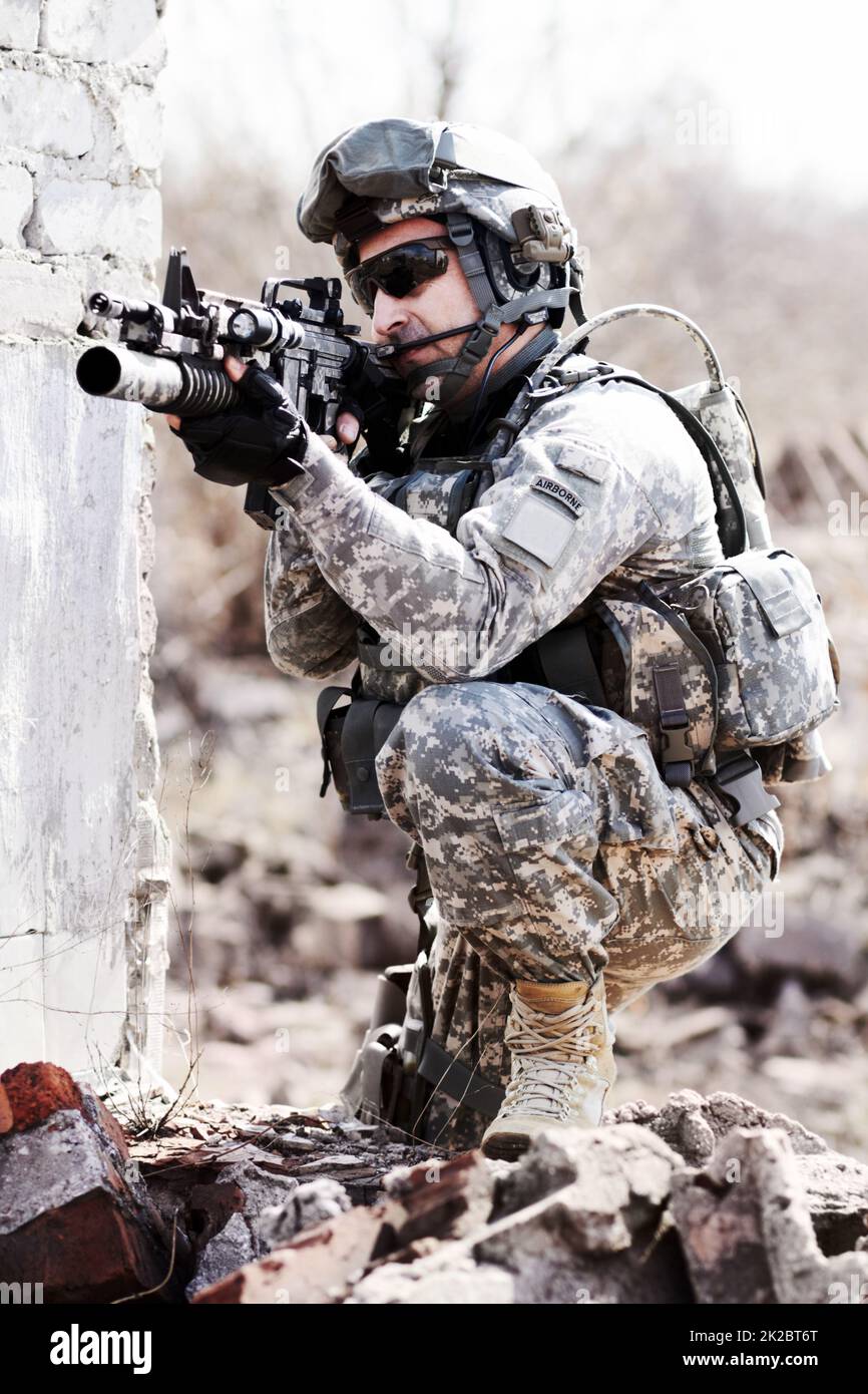 Leading the assult. A soldier crouched down next to a broken down wall