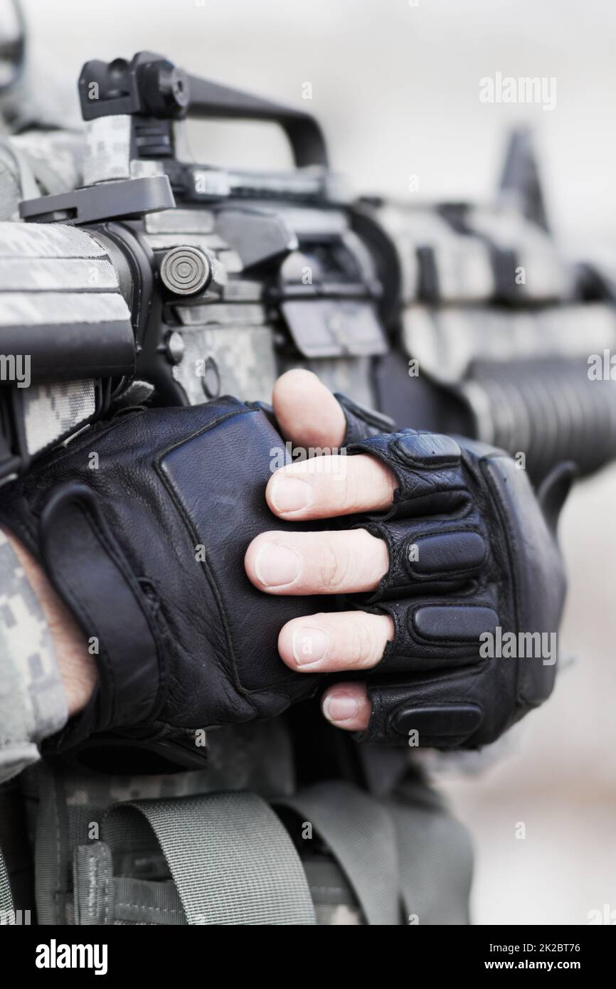 At ease soldier. Closeup cropped shot of the midriff of a soldier holding his gun against his chest. Stock Photo