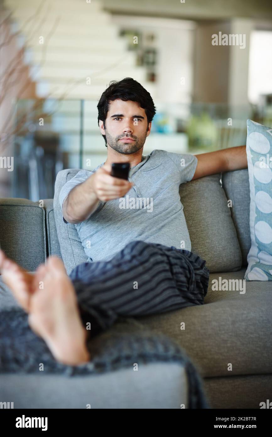 Checking whats on the telly. Portrait of a man sitting on his couch watching television. Stock Photo