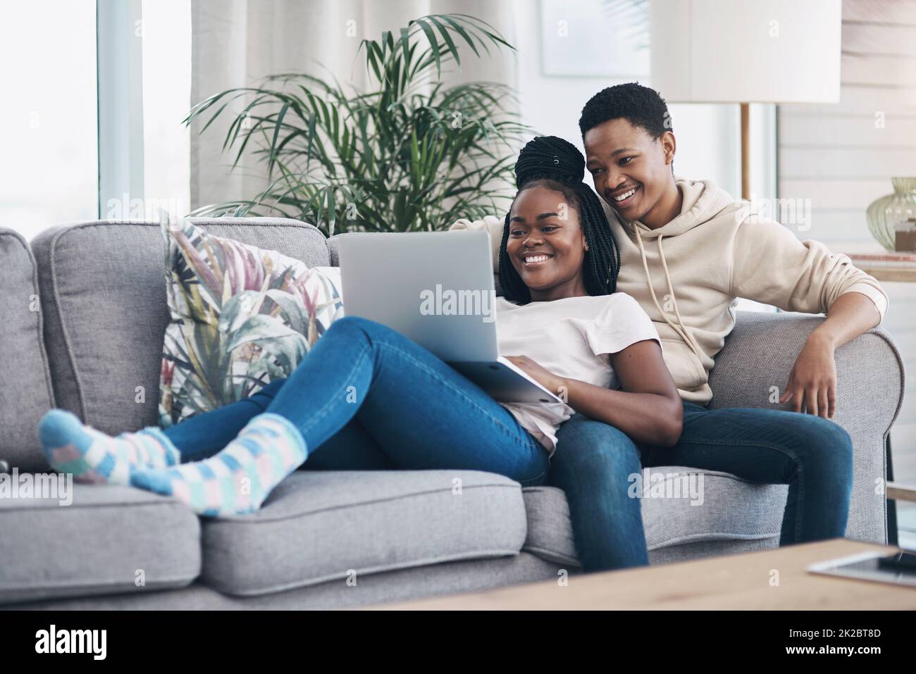 Nothing says romance like a cosy weekend at home. Shot of a young couple using a laptop while relaxing on the sofa at home. Stock Photo