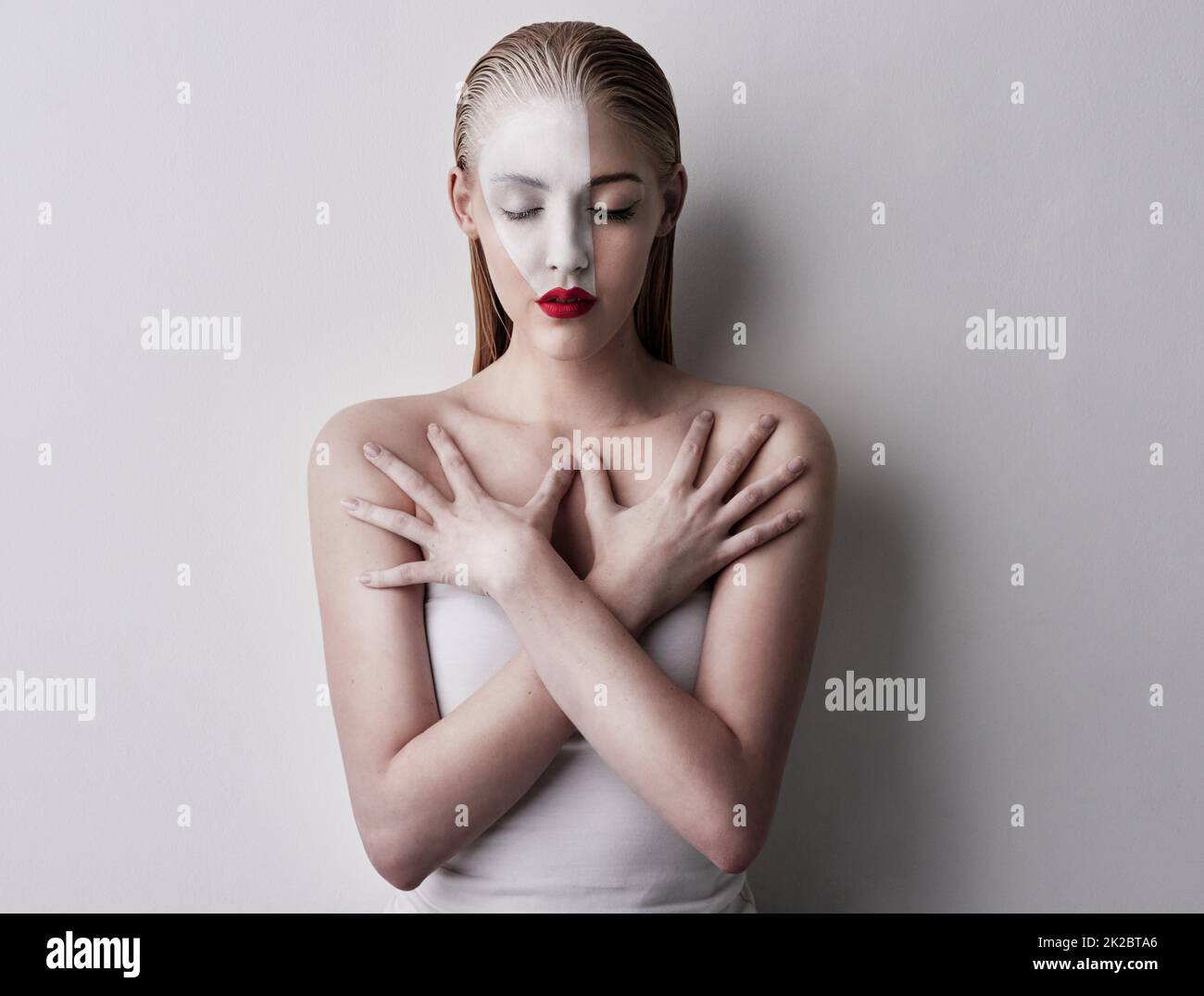Highlight what you want to highlight. Shot of a beautiful woman wearing face paint and red lipstick against a plain background. Stock Photo