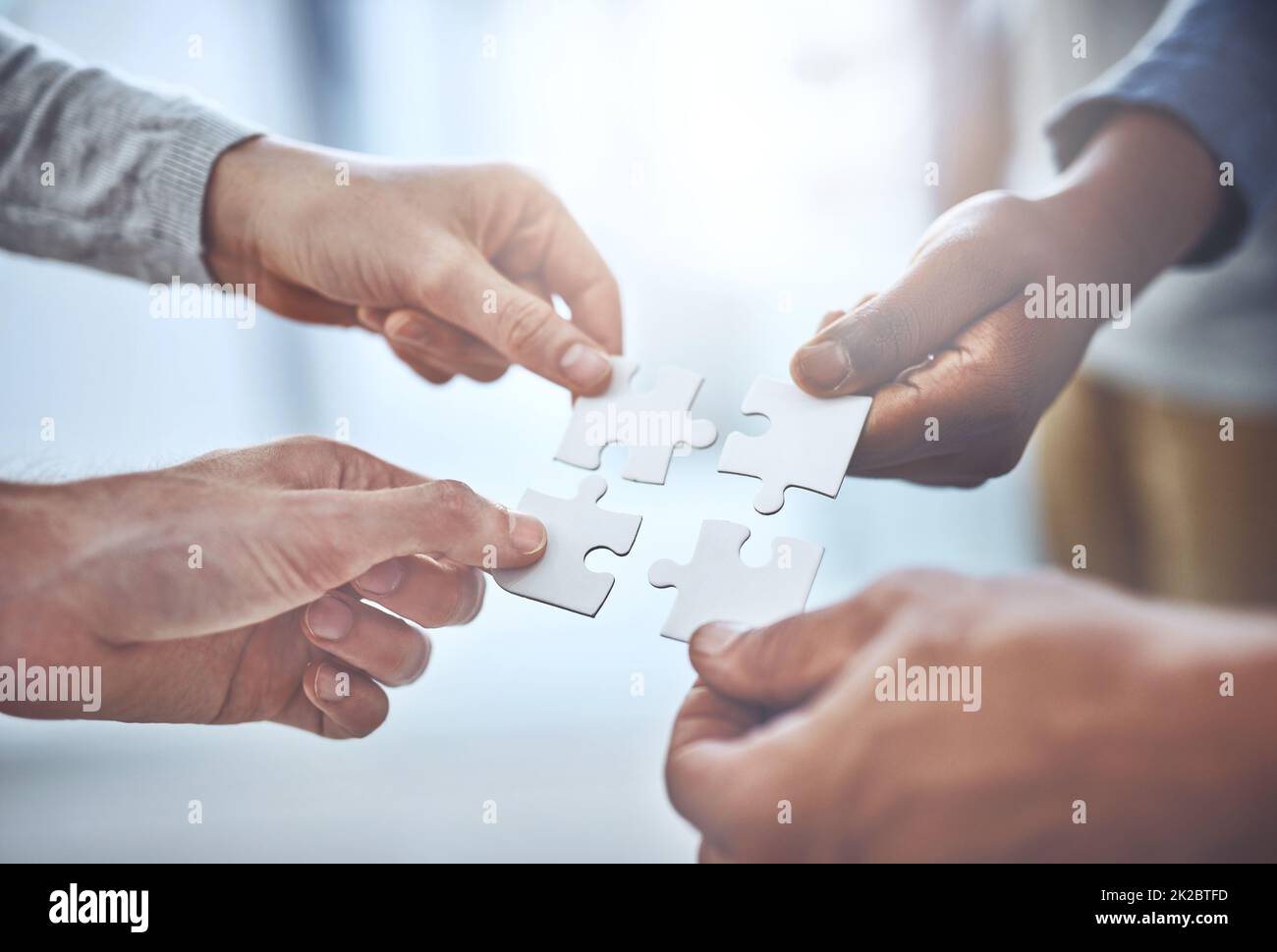 We can solve anything as a team. Closeup shot of a group of unrecognisable businesspeople holding puzzle pieces together. Stock Photo