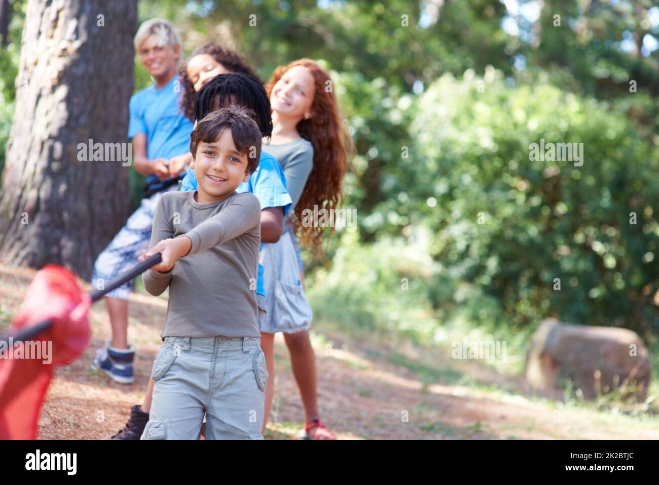 Pull. Children playing at tug-of-war in the woods. Stock Photo