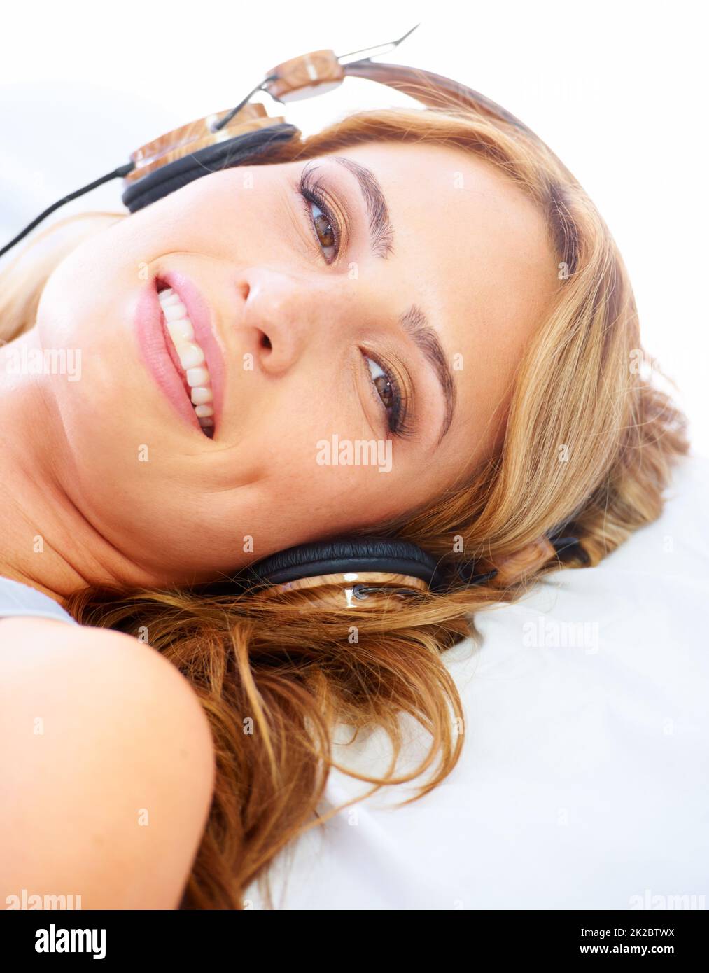 Relaxing with some great sounds. Young woman listening to music while wearing a pair of headphones and smiling. Stock Photo
