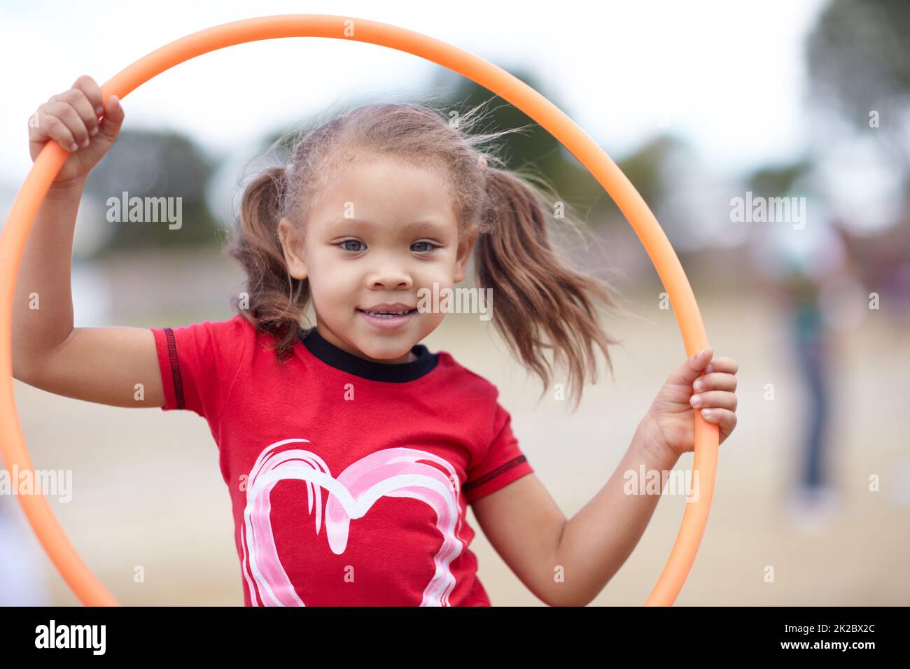 Little miss hula hoop. Cute little preschooler playing with a hula hoop while outdoors. Stock Photo