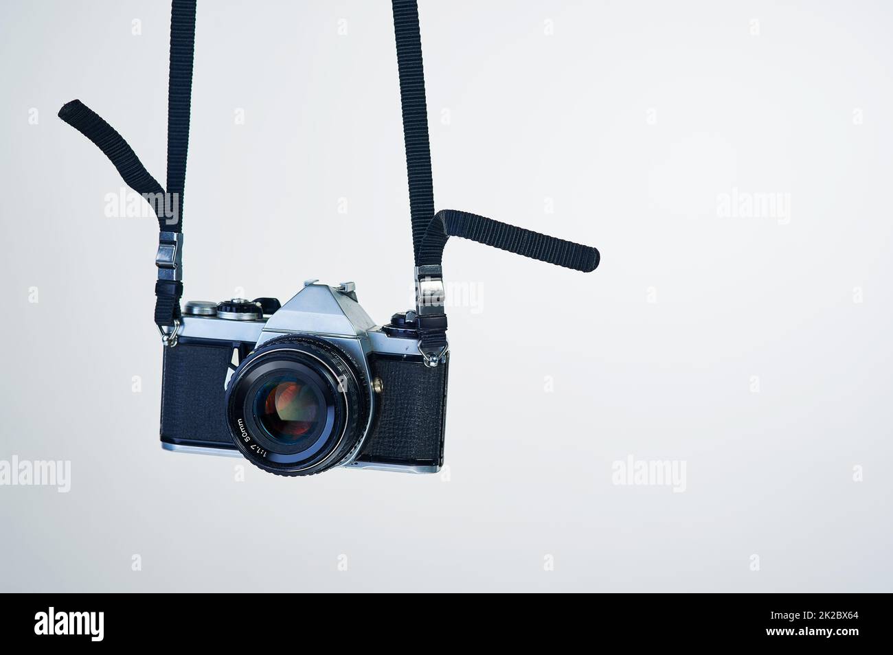 Film photography makes a comeback. Studio shot of a camera hanging by its strap. Stock Photo