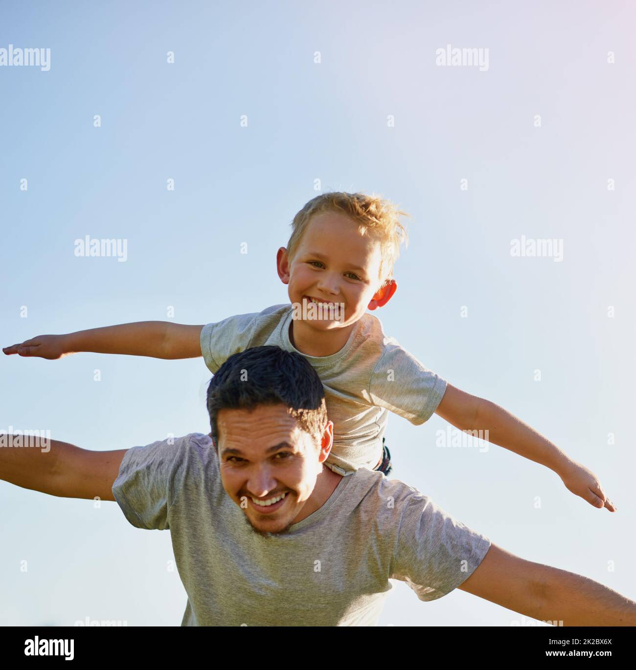 Letting his sons imagination soar. Shot of a father giving his son a piggyback on a sunny day. Stock Photo