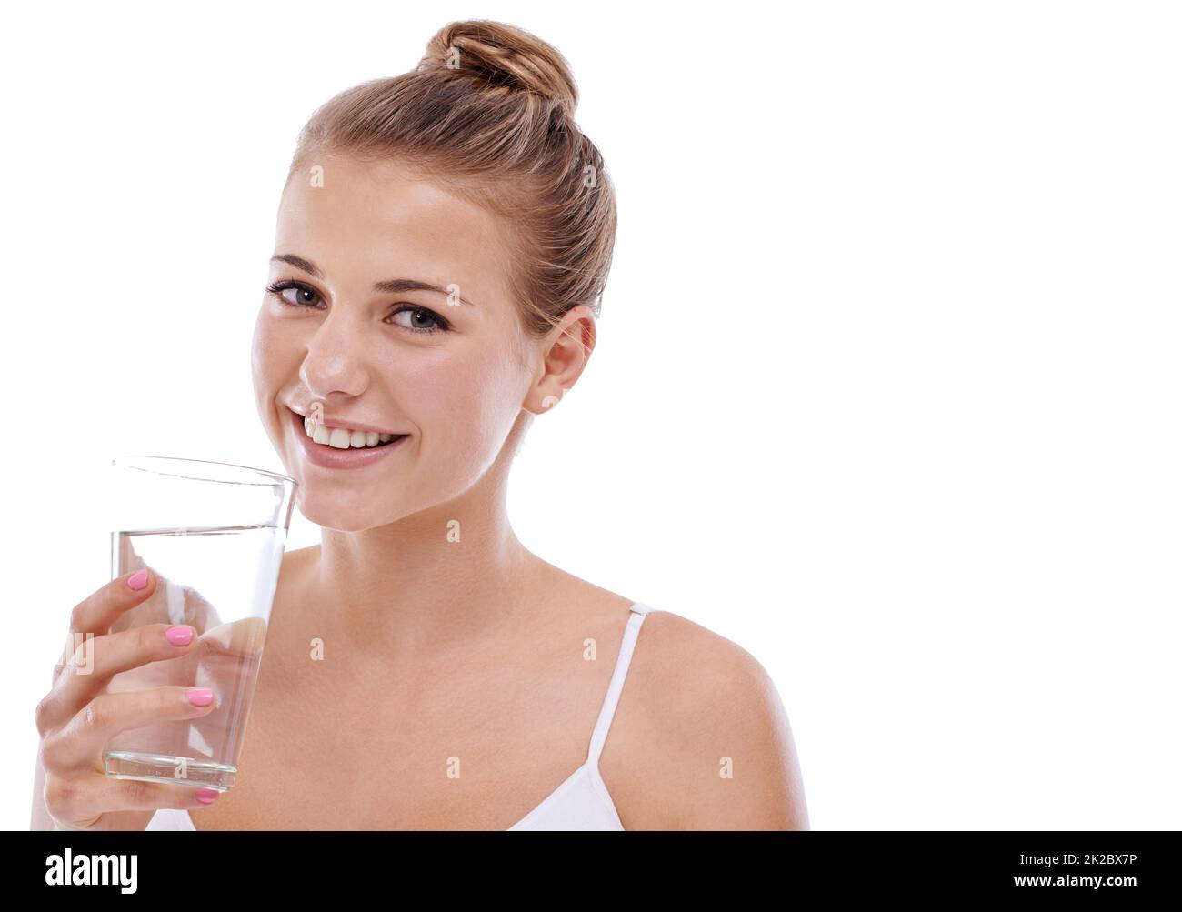Its her beauty secret. A cute young girl with perfect skin drinking water while isolated on white. Stock Photo