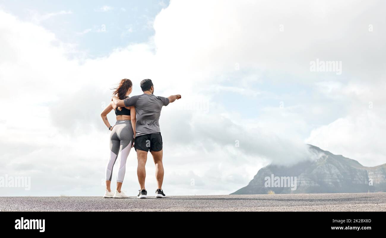 Thats what well conquer next. Rearview shot of a sporty young man and woman looking at the view while exercising outdoors. Stock Photo
