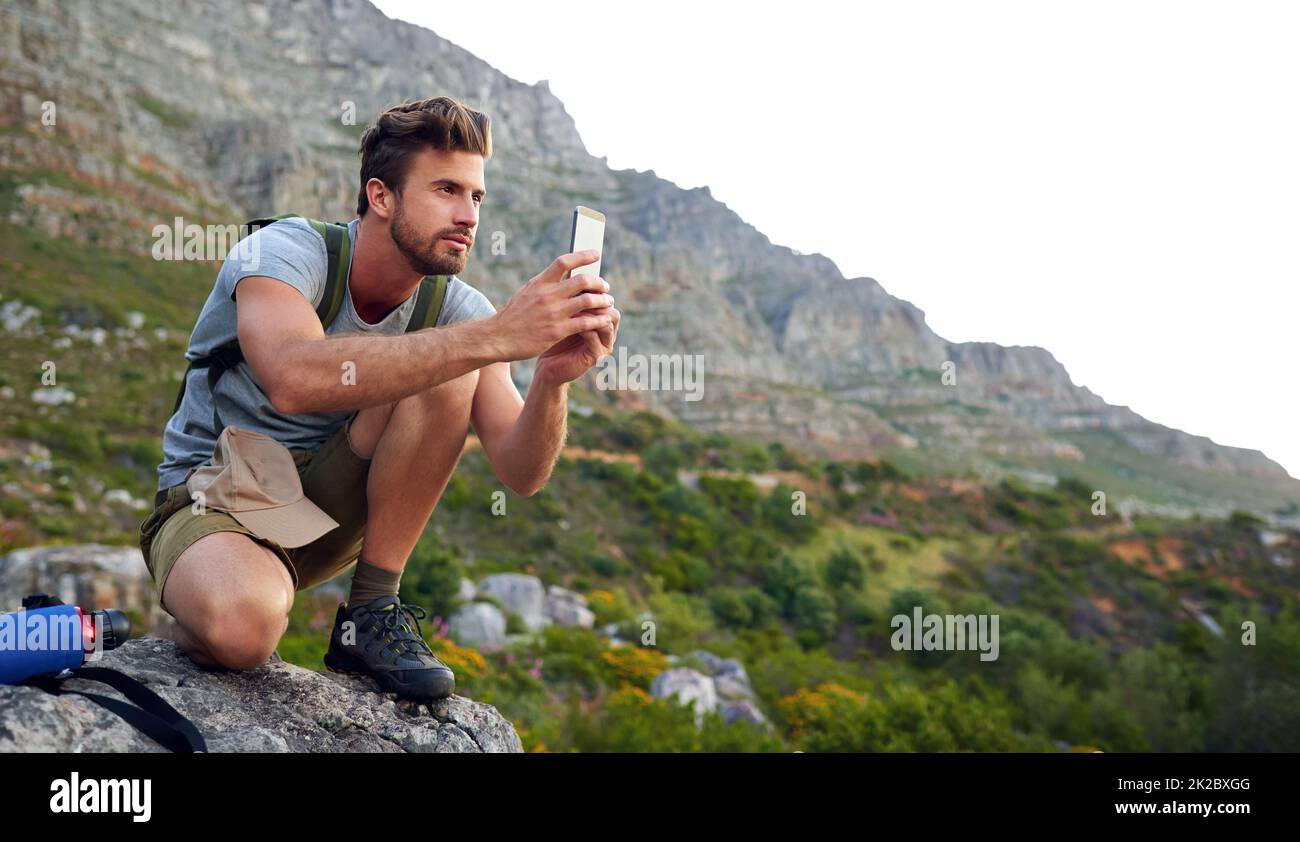 Ive gotta get some pics. Shot of a handsome young man snapping pics while hiking. Stock Photo