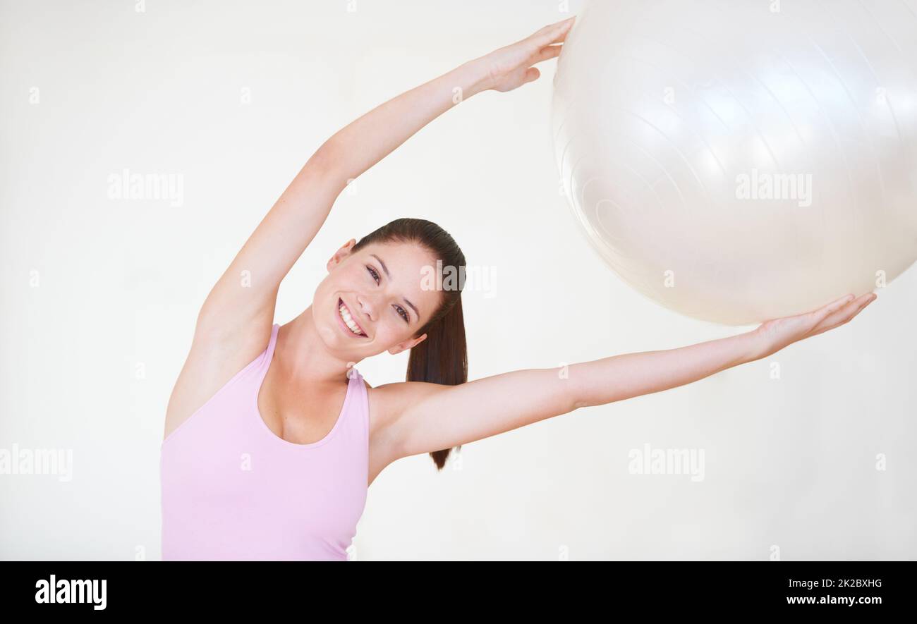 Stretching is key to fitness. Shot of an attractive young woman with her arms stretched above her head holding an exercise ball. Stock Photo