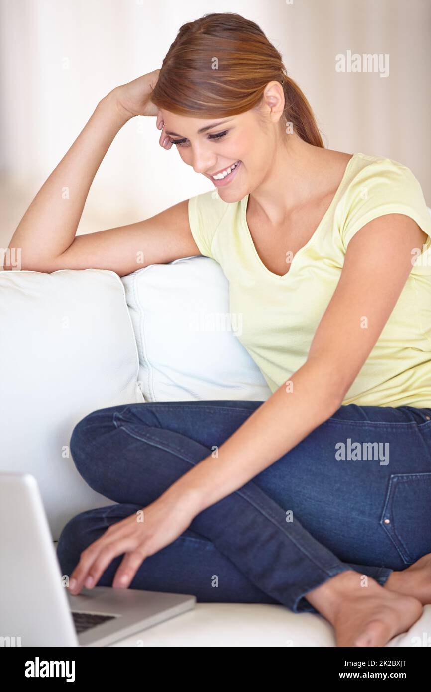 My friends always put me a good mood - Online messaging. Cropped shot of an attractive young woman using her laptop while relaxing on her sofa at home. Stock Photo