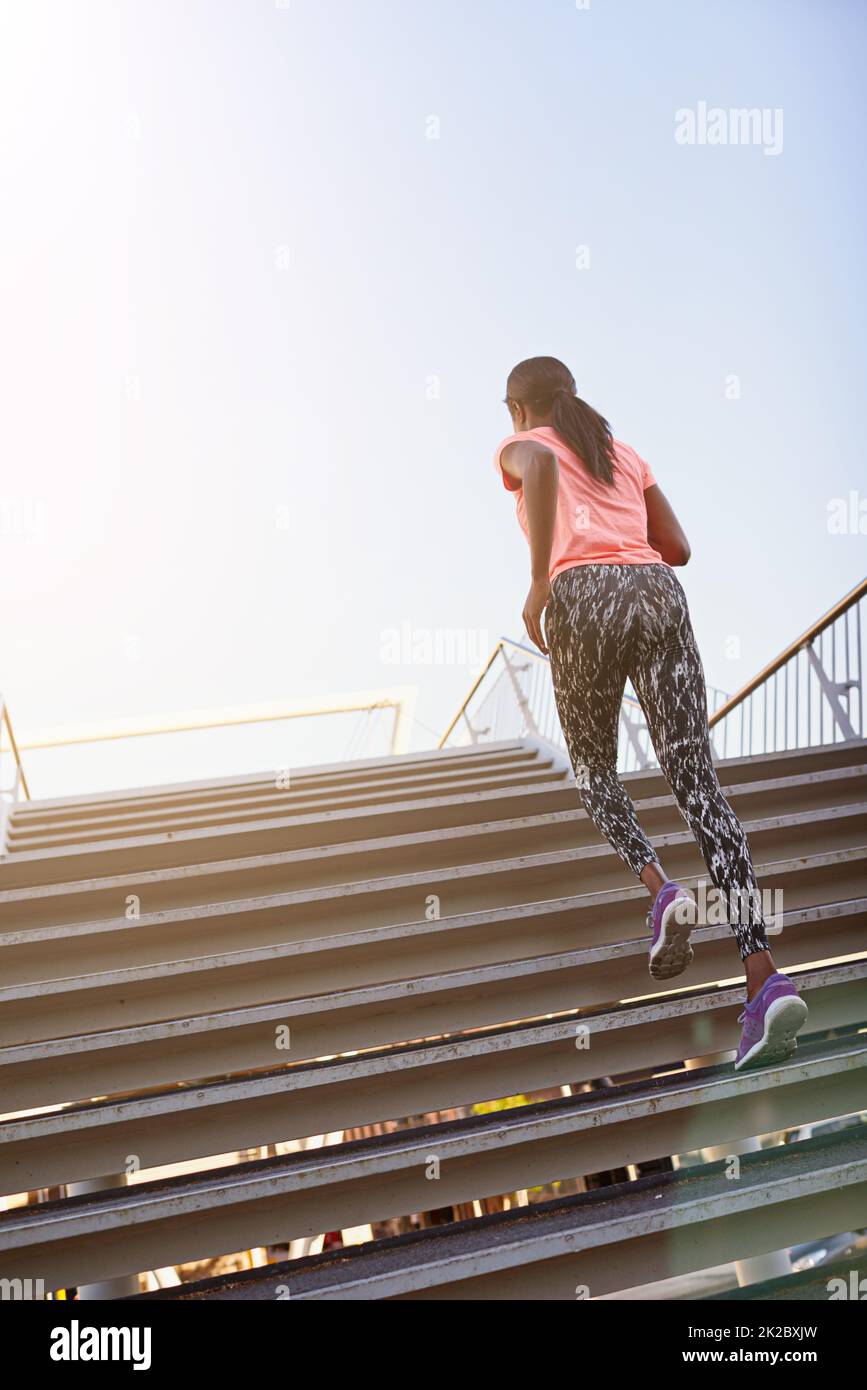 Doing her Rocky impression. Rearview shot of a young female athlete running up and down the bleachers. Stock Photo