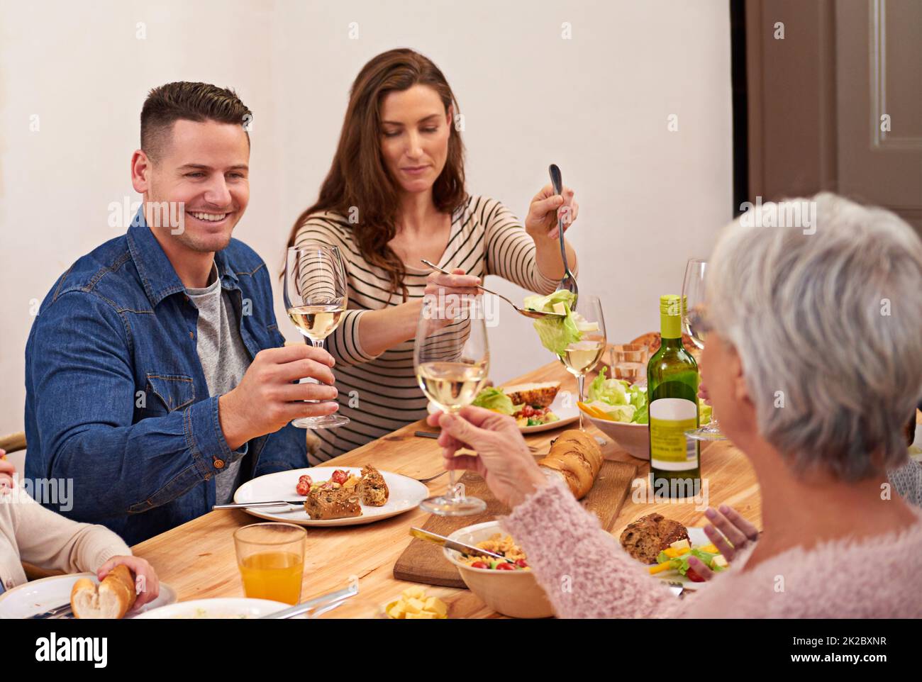 Cheers. Cropped shot of a family sharing a meal around the dinner table. Stock Photo