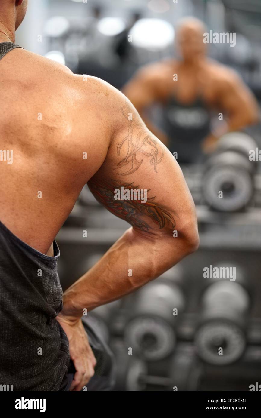 He is ripped. A muscular bodybuilder flexing his muscles while watching