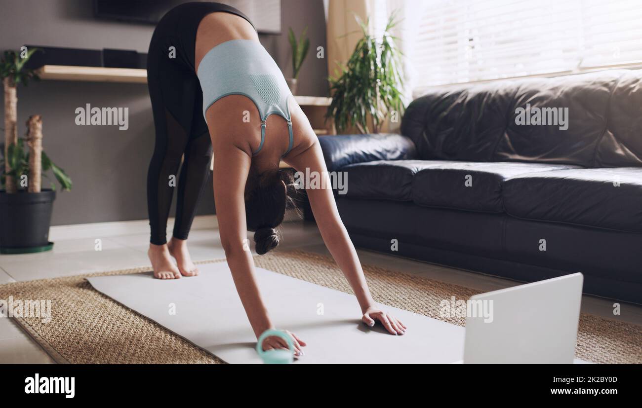 This is great for my back. Shot of a young woman practising a yoga routine at home. Stock Photo