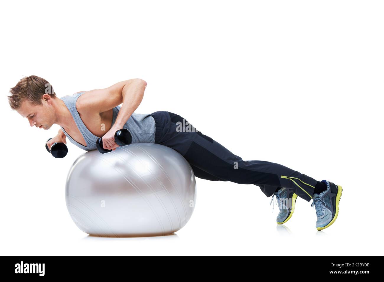 Really working those arms. Shot of a man balancing on an exercise ball lifting weights. Stock Photo