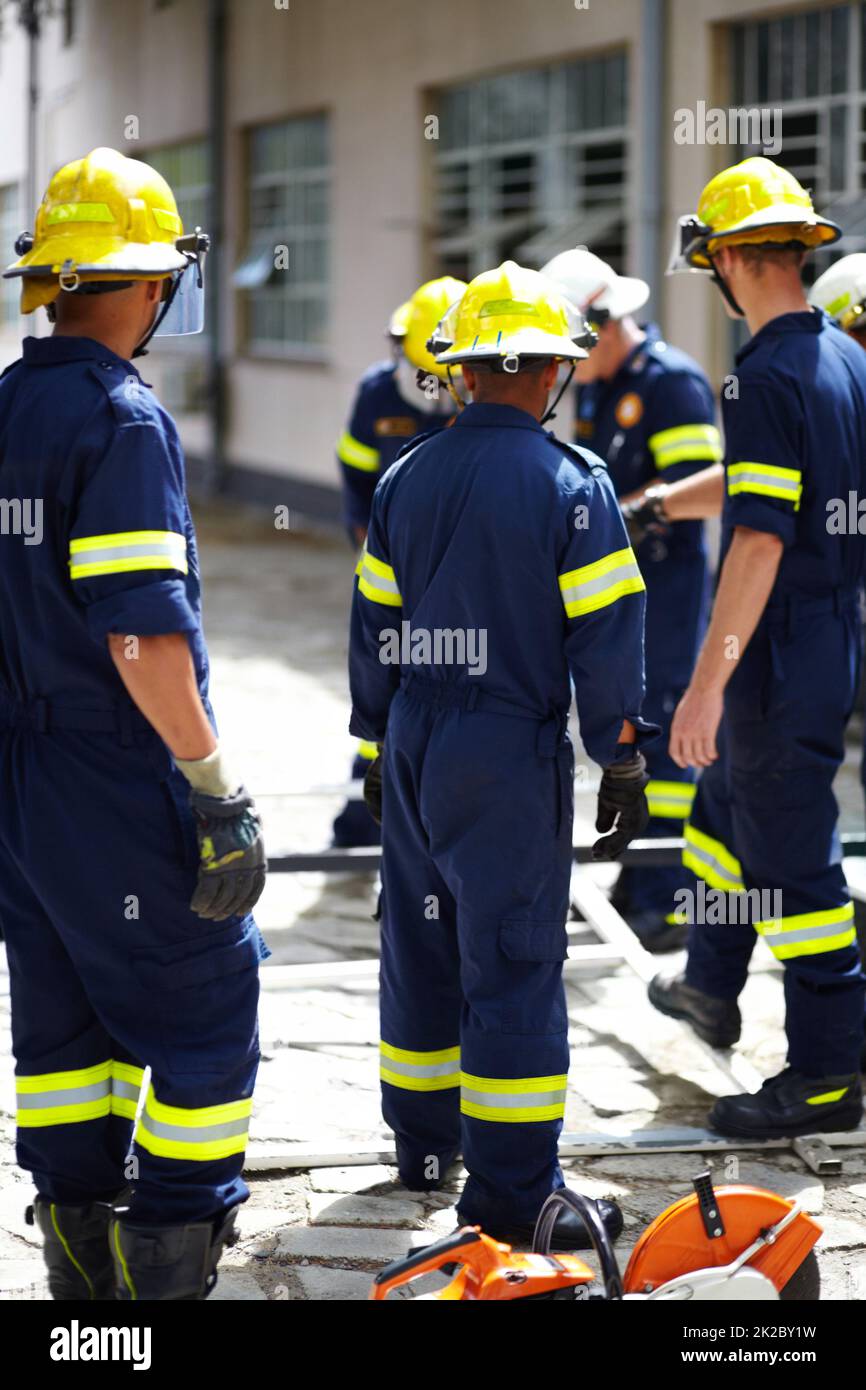 Theyve got the situation under control. Shot of a group of firemen standing outside a fire station. Stock Photo