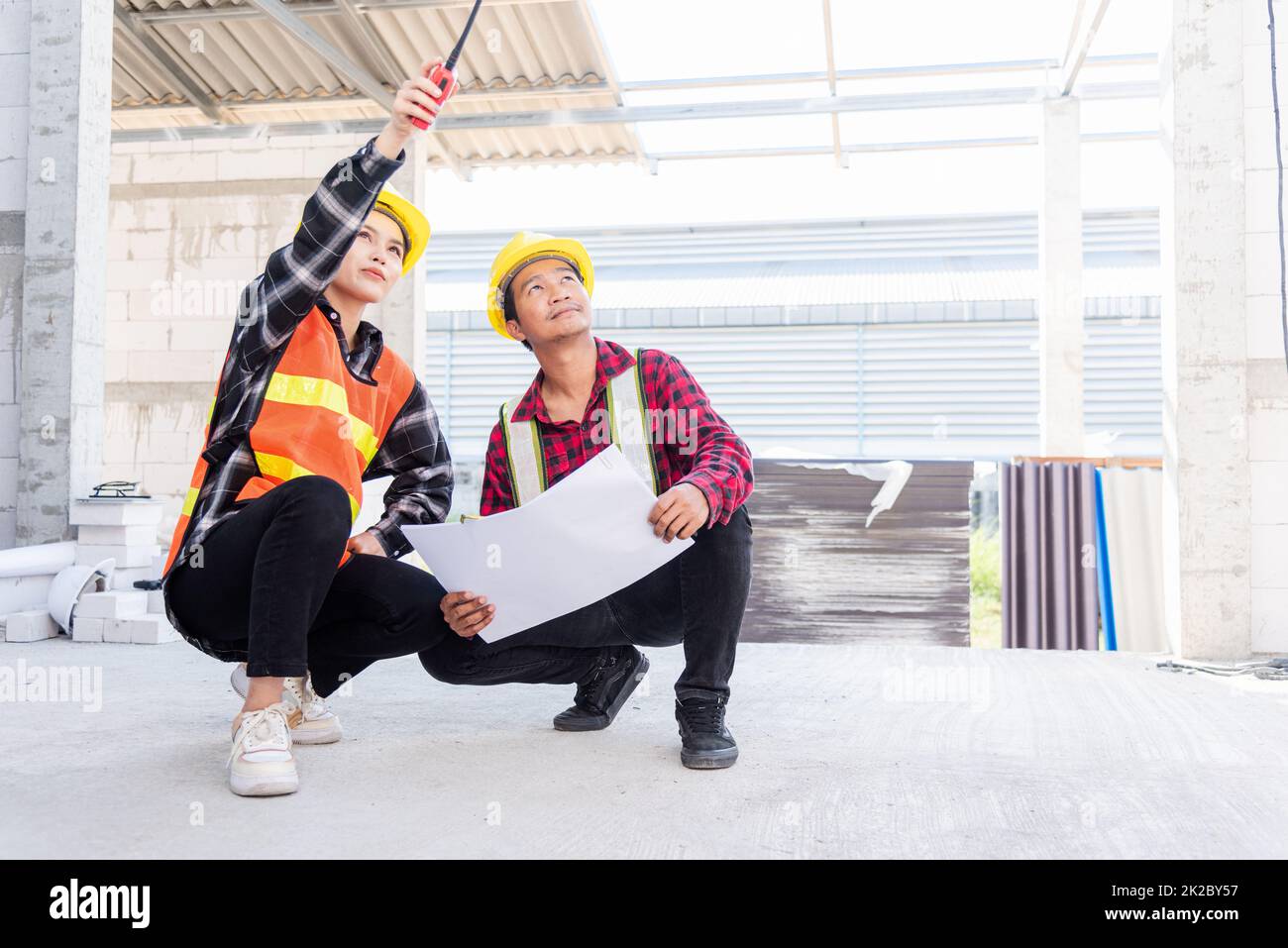 Architect and client discussing help create plan with blueprint of the building at construction site. Asian engineer foreman worker man and woman meeting talking on drawing paper project, team work Stock Photo