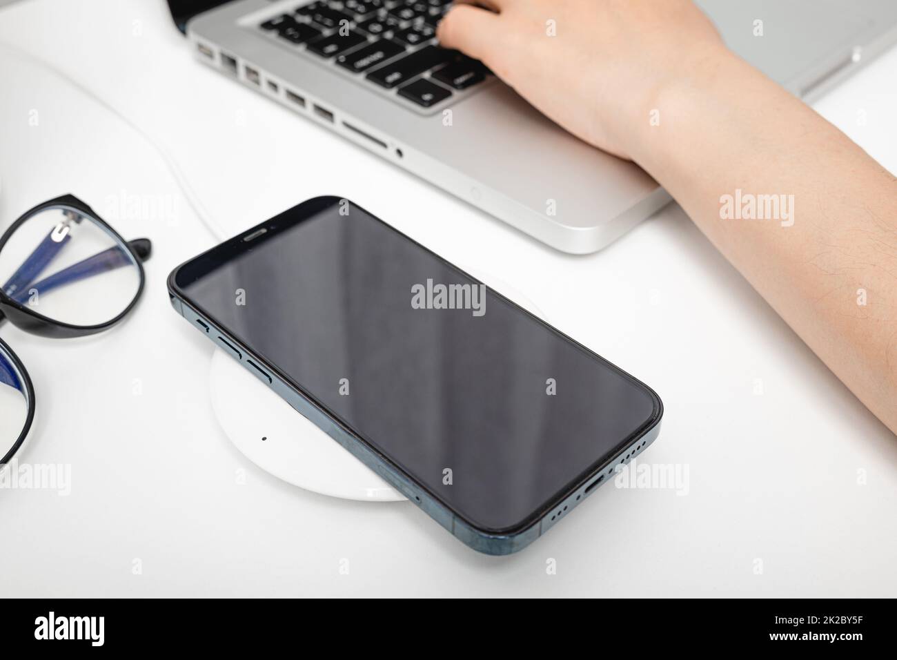 Charging smartphone battery with wireless charger device Stock Photo