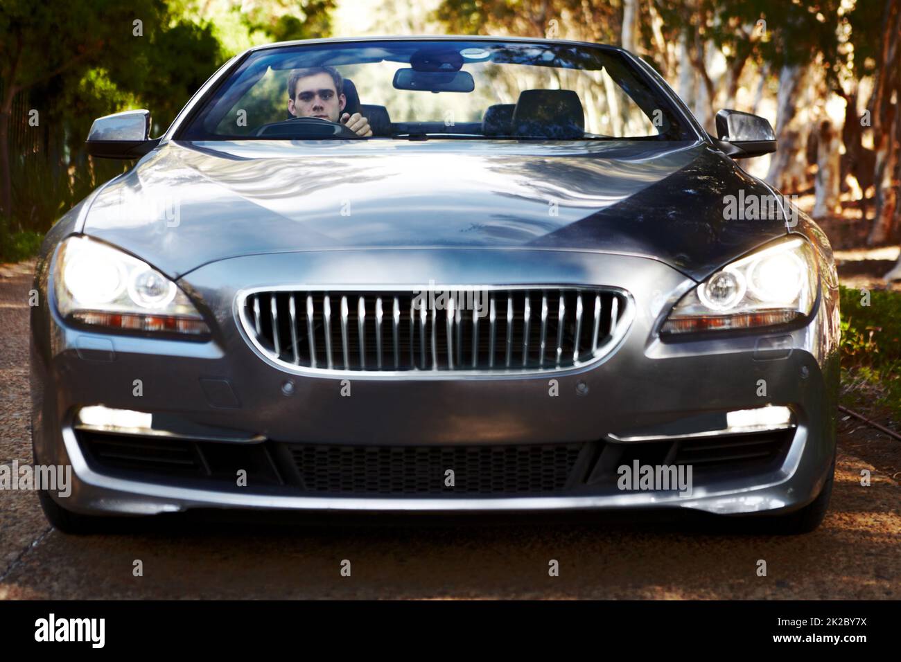 Hes serious about driving. Portrait of a man sitting his silver sportscar which is facing you. Stock Photo