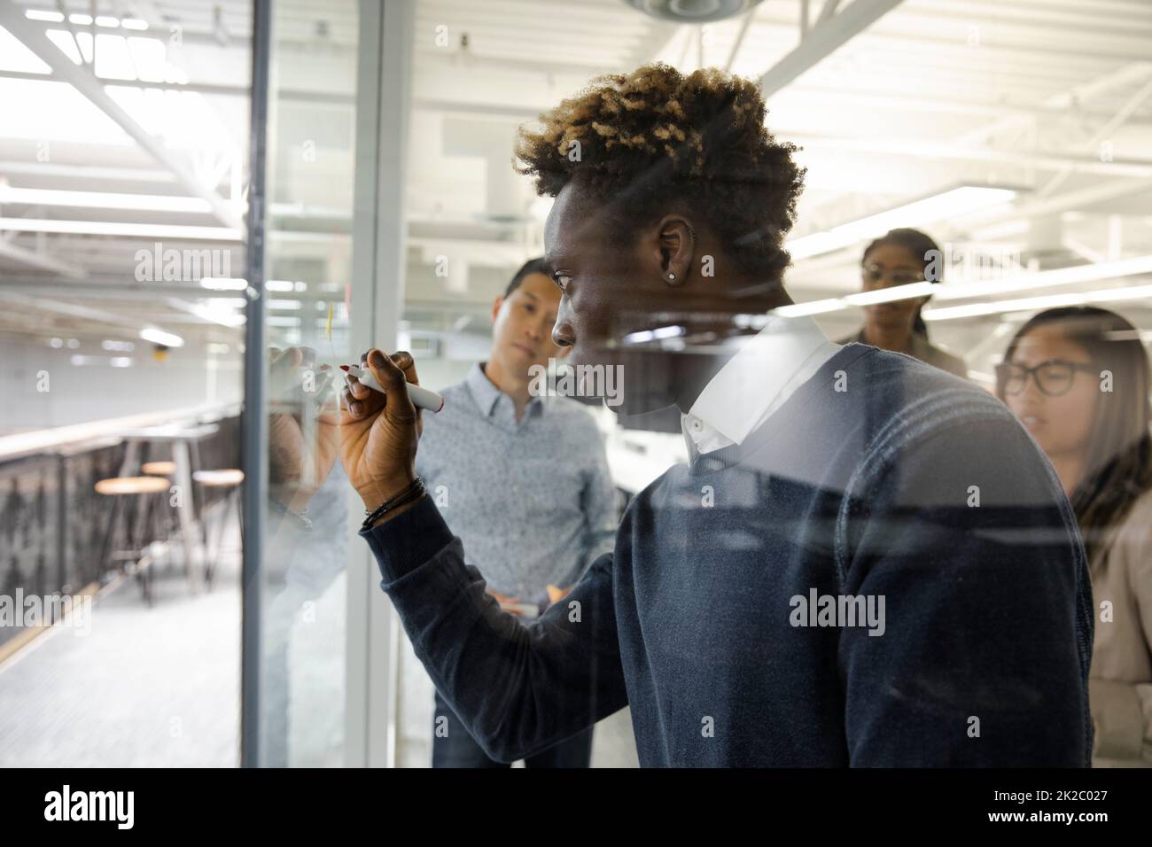 Man using glass screen to demonstrate to meeting Stock Photo