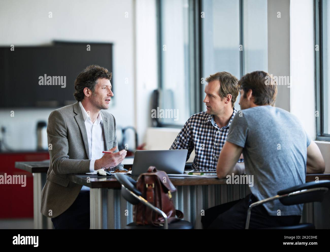 Getting his ideas across. three businessman discussing work in the office. Stock Photo