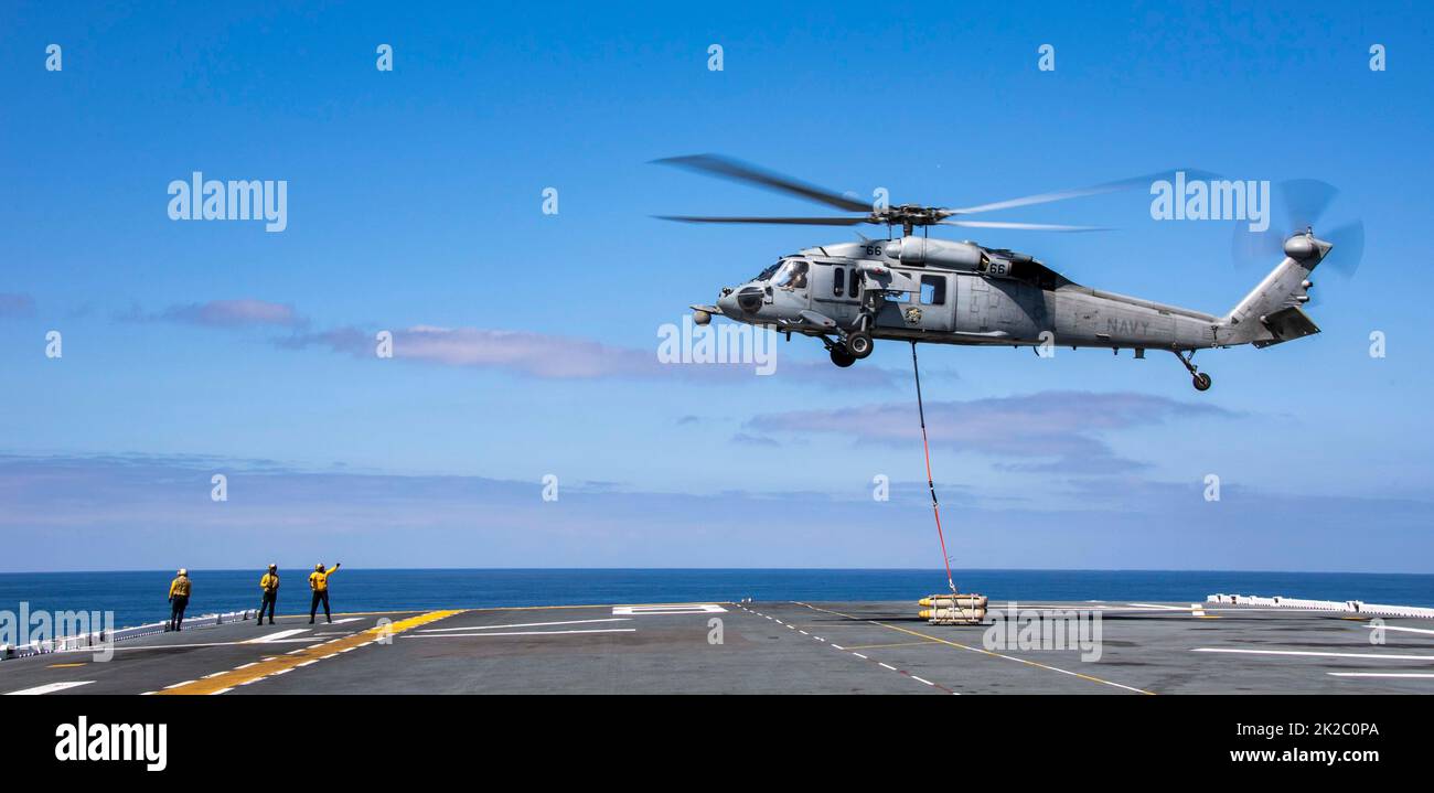 220915-N-EI127-1119    PACIFIC OCEAN (Sept. 15, 2022) – An MH-60S Sea Hawk helicopter, assigned to Helicopter Sea Combat Squadron (HSC 21), drops off ordinance during an ammunition onload aboard amphibious assault ship USS Makin Island (LHD 8), Sept. 15 Aviation Ordnancemen operate and handle aviation ordnance equipment and are responsible for the stowage and loading of munitions and small arms. The Makin Island Amphibious Ready Group, comprised of amphibious assault ship USS Makin Island (LHD 8) and amphibious transport docks USS Anchorage (LPD 23) and USS John P. Murtha (LPD 26), is underway Stock Photo
