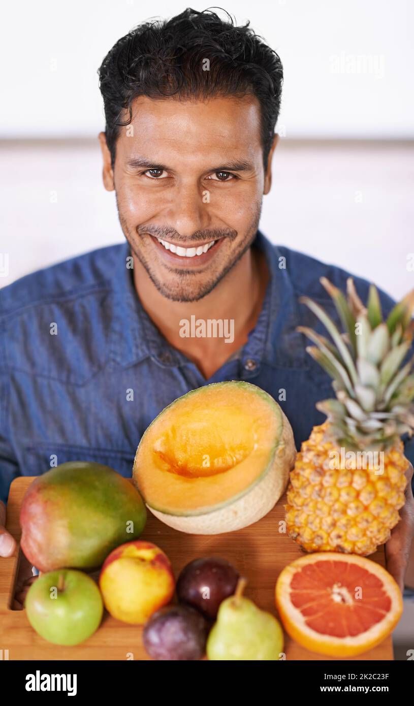 Take your pick. Portrait of a handsome man holding up a chopping board full of fruit. Stock Photo