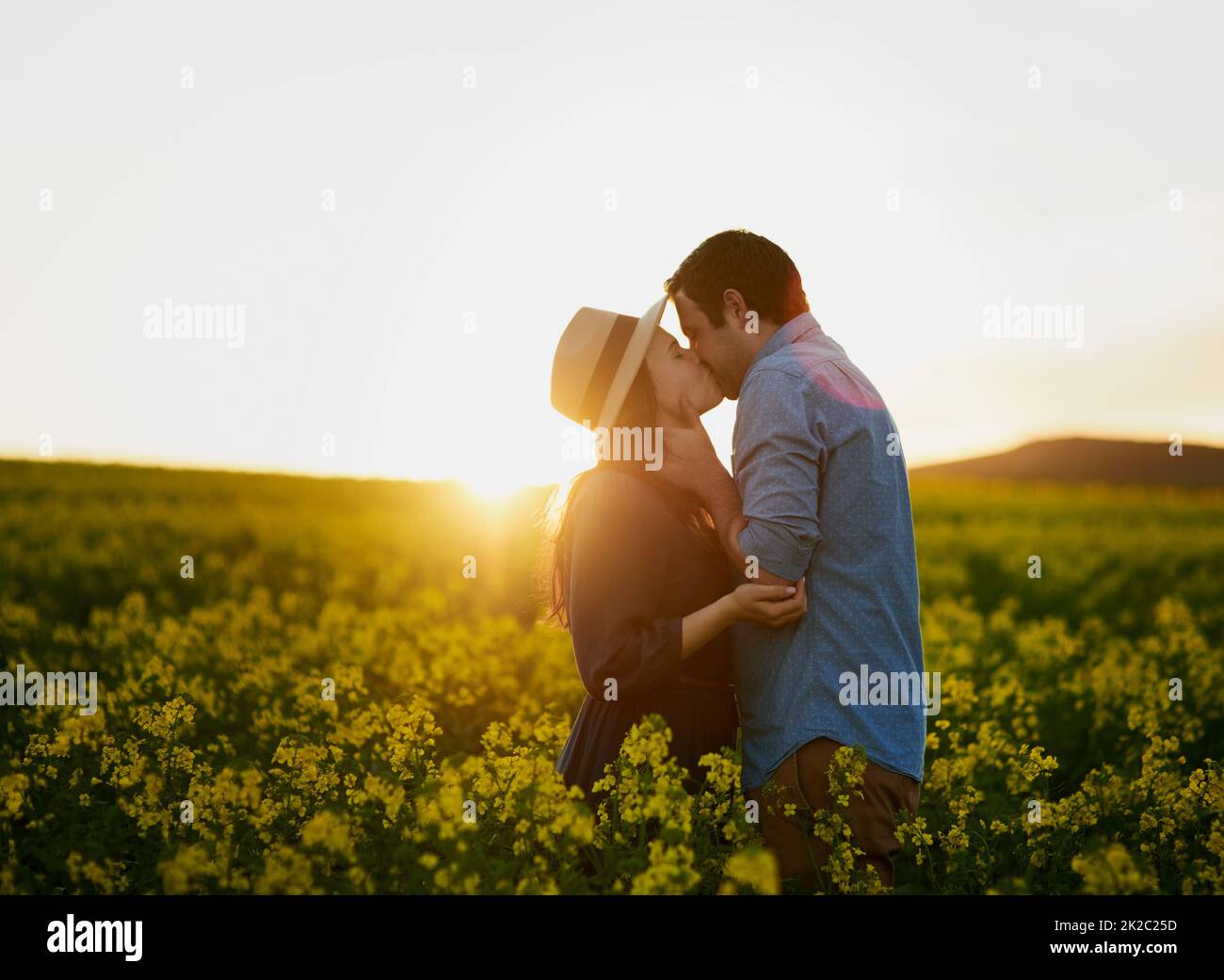 Sharing a magical moment together. Shot of an affectionate young couple sharing a kiss at sunset. Stock Photo