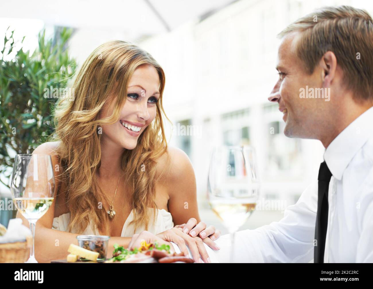 Her first date after plastic surgery. A woman with cosmetic enhancements admiring her boyfriend in a restaurant. Stock Photo