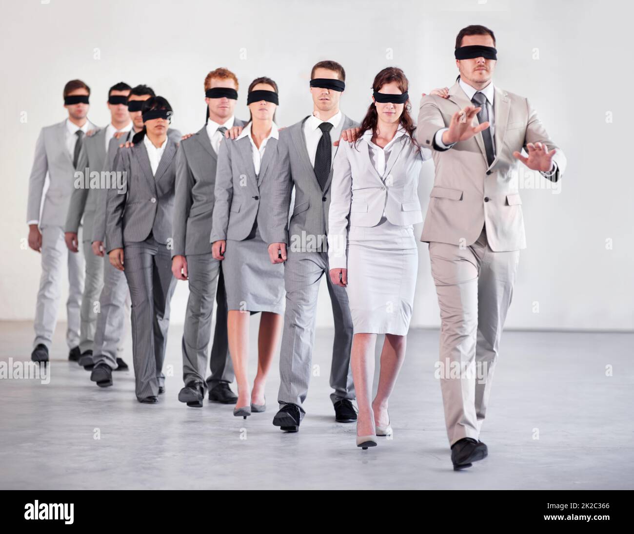 Business without strategy is chaos. Shot of a group of blindfolded businesspeople following their equally blind manager. Stock Photo