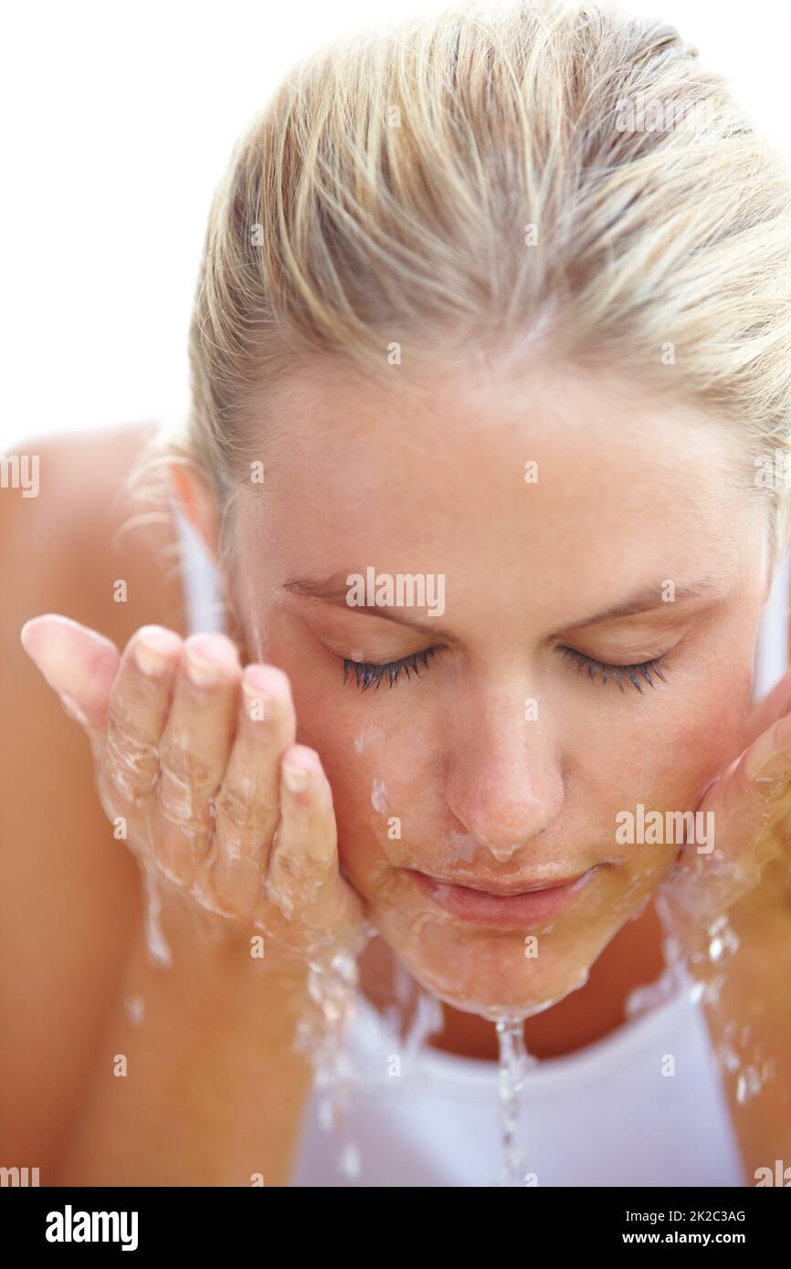 Waking herself up. An attractive young woman washing her face with water. Stock Photo