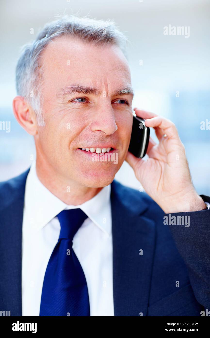 Executive discussing business deal. Man in suit smiling while talking on cell phone. Stock Photo