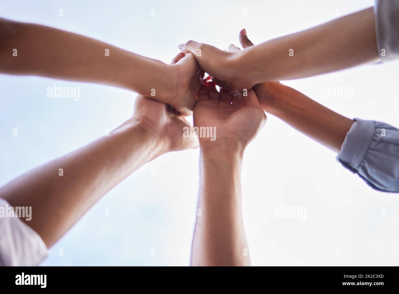 Were a team that stays motivated. Low angle shot of an unrecognisable group of businesspeople standing together and giving each other a high five. Stock Photo