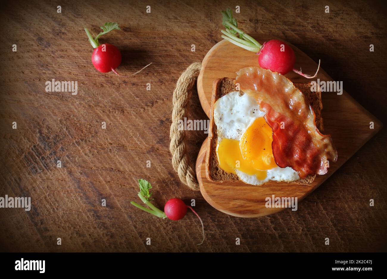 Breakfast , crispy bacon, fried eggs and bread. Sandwich on cutting board. Rustic table . Top view Stock Photo