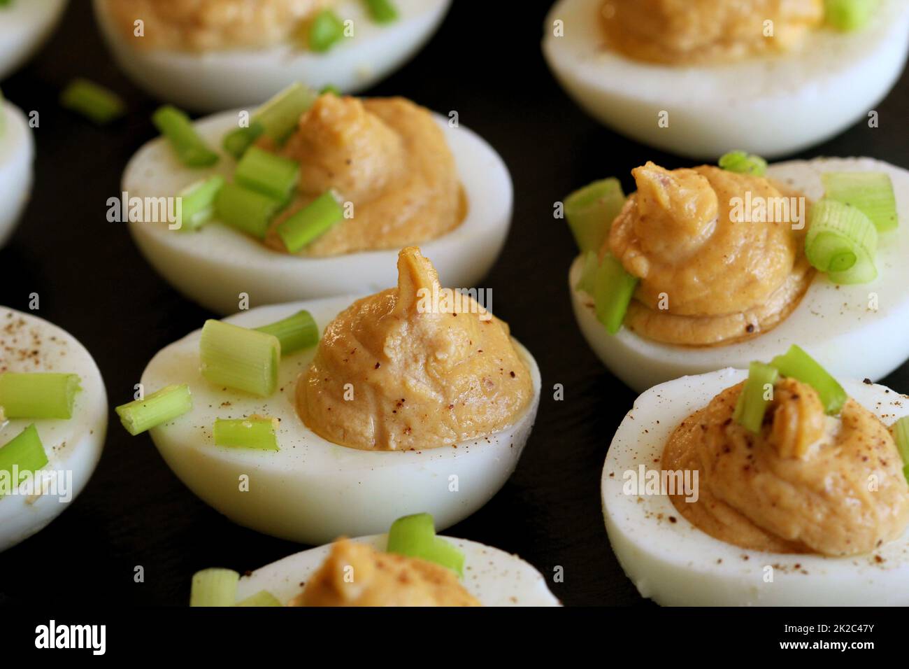 Deviled eggs with cod livers with leek on on black background Stock Photo