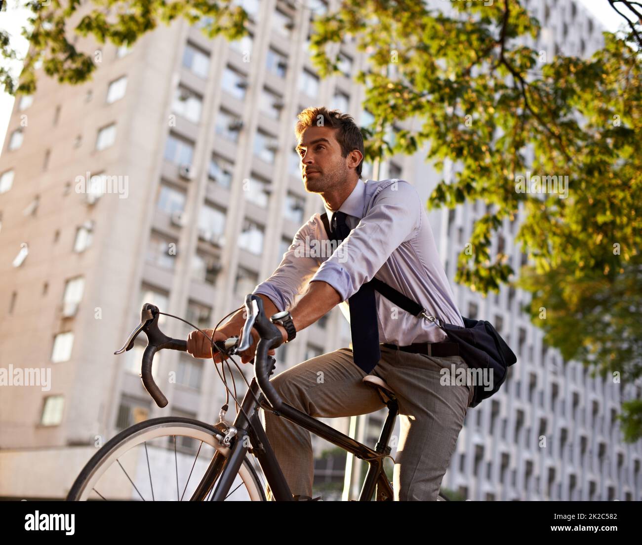 Off to work on his wheels. Shot of a businessman commuting to work with his bicycle. Stock Photo