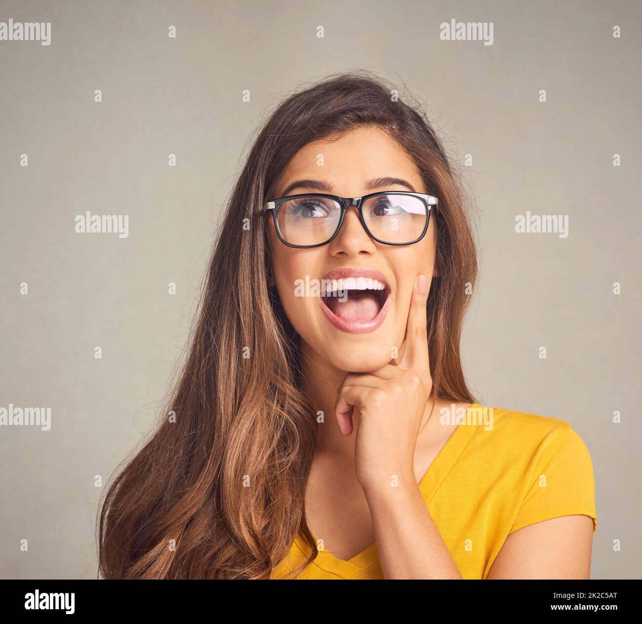 So theres this boy.... Closeup of an expressive young woman against a grey background. Stock Photo